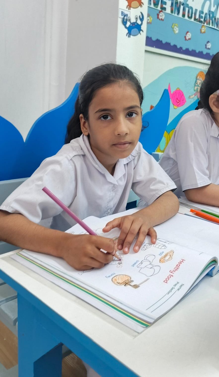 A Warsis student looking up from her classroom worksheet