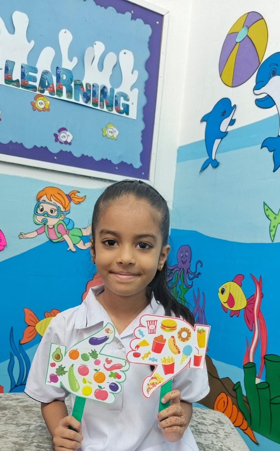 A Warsis student holding the healthy-food and junk-food paddles she made in class