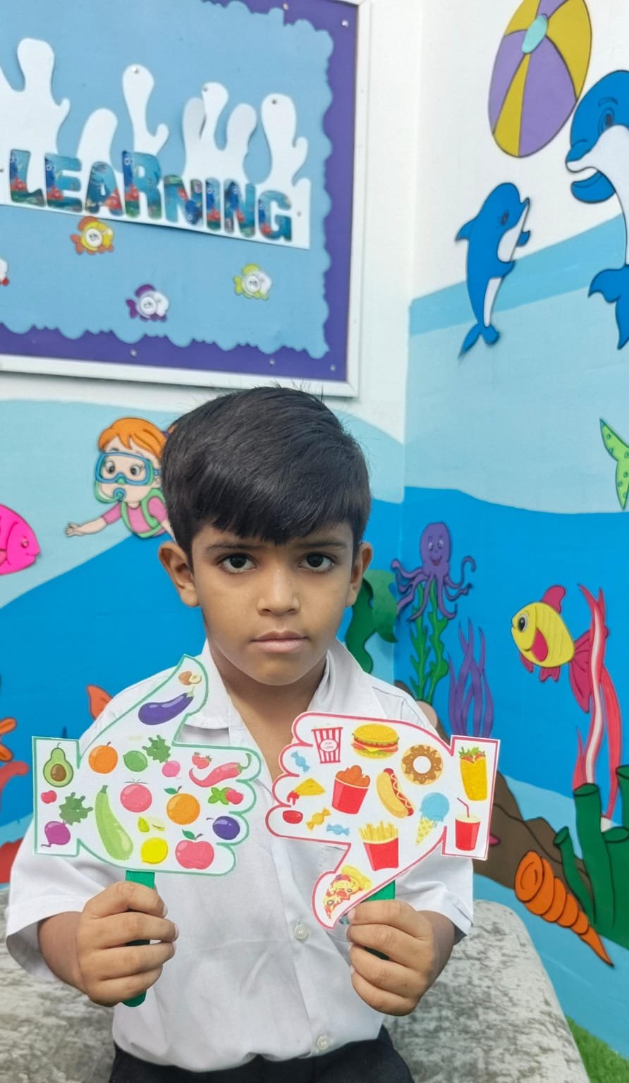 A Warsis student presenting his healthy-food and junk-food paddles