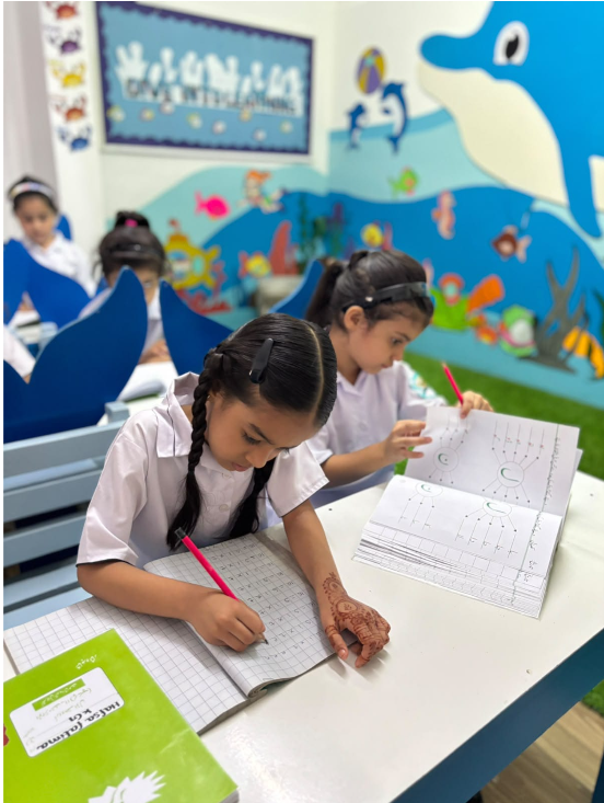 Two Warsis students forming letters in their handwriting books