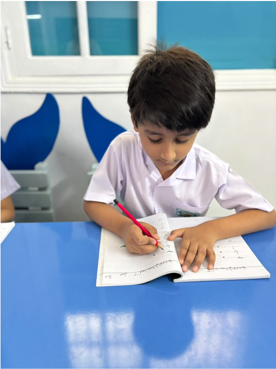 A young Warsis student concentrating on his handwriting exercise