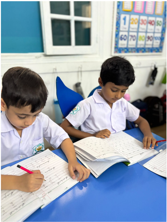 Two Warsis Primary students writing side by side in their notebooks